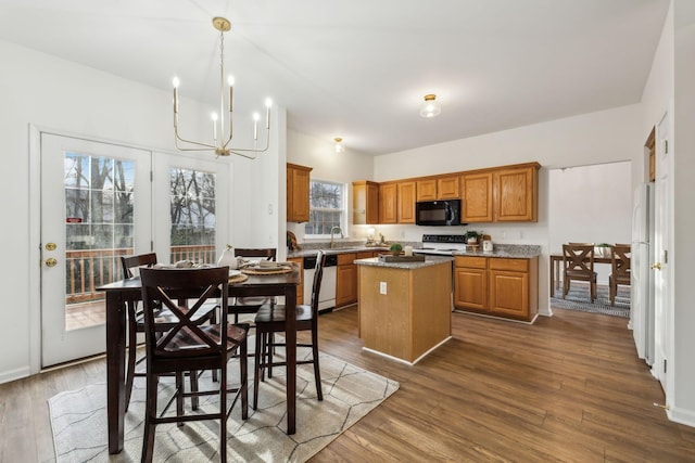 kitchen featuring a center island, black appliances, sink, dark hardwood / wood-style floors, and a chandelier