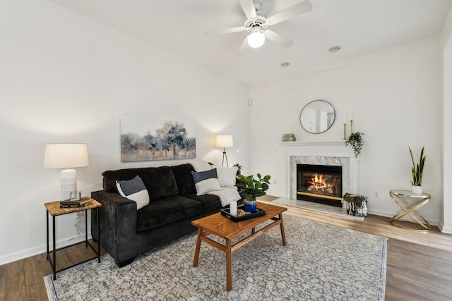 living room featuring a high end fireplace, hardwood / wood-style floors, and ceiling fan