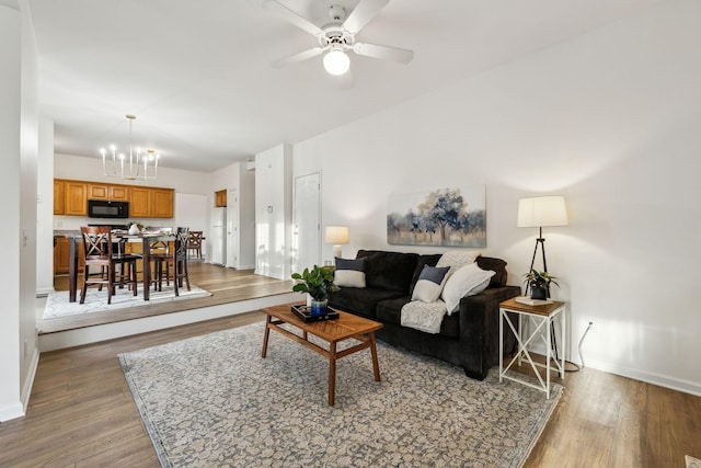 living room with hardwood / wood-style floors and ceiling fan with notable chandelier