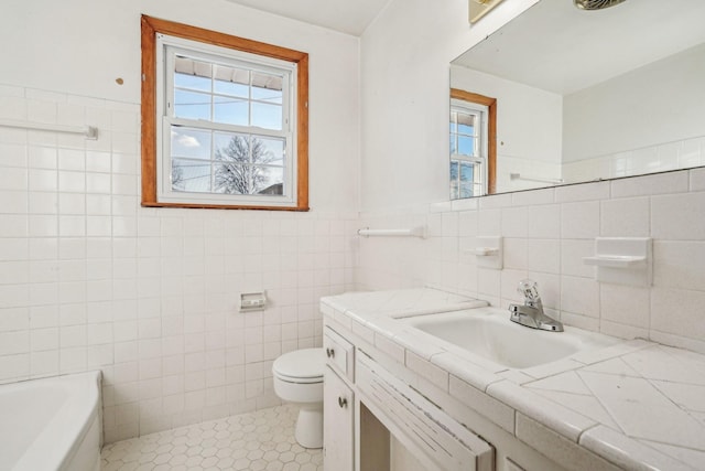 bathroom with tile patterned flooring, a bathtub, toilet, and tile walls