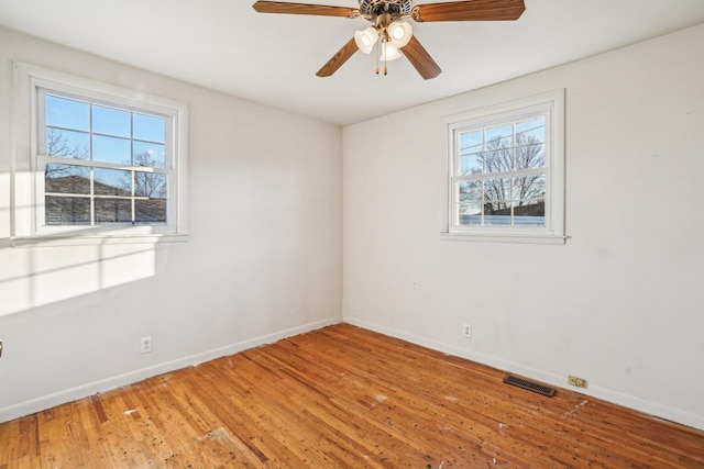 empty room with wood-type flooring, plenty of natural light, and ceiling fan