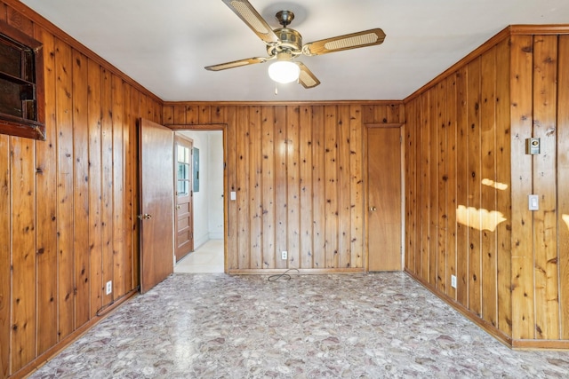 unfurnished room featuring ceiling fan, wood walls, and ornamental molding