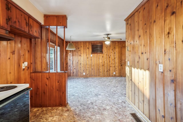 kitchen featuring electric range, ceiling fan, hanging light fixtures, and wooden walls