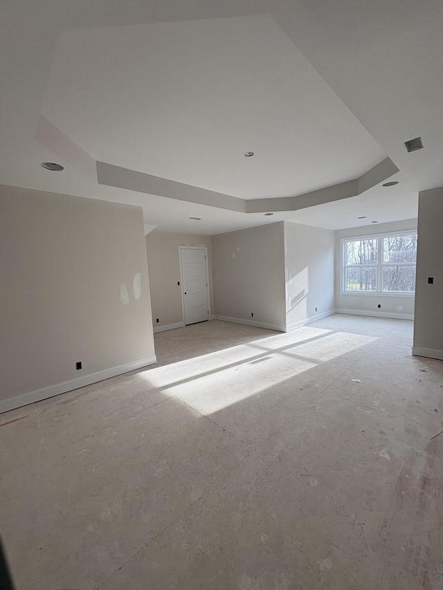 unfurnished room featuring a tray ceiling, baseboards, and visible vents