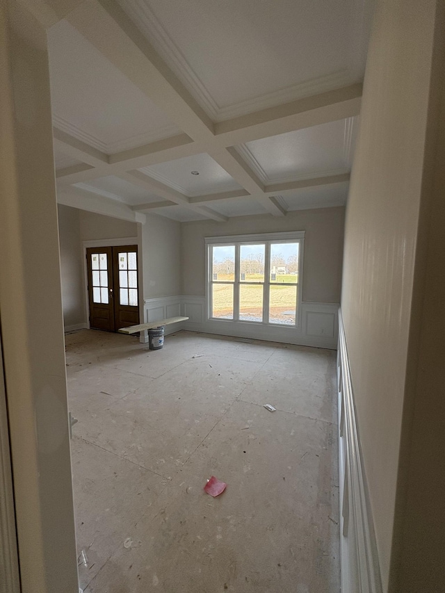 empty room featuring beam ceiling, ornamental molding, coffered ceiling, french doors, and wainscoting