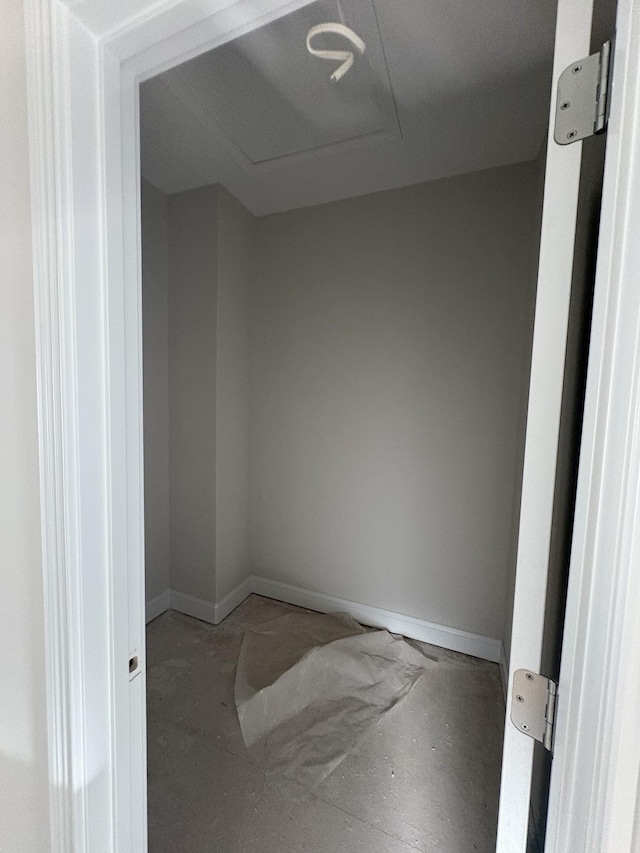 spare room featuring attic access and baseboards