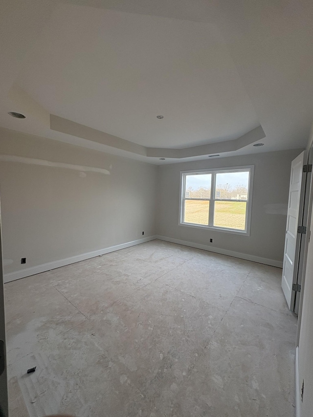 unfurnished room with a tray ceiling and baseboards