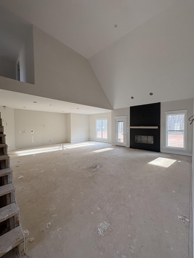 unfurnished living room featuring plenty of natural light, a fireplace, and high vaulted ceiling