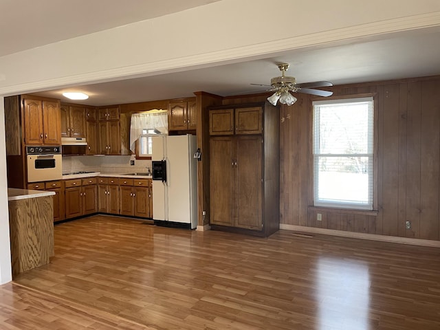 kitchen with wooden walls, sink, dark wood-type flooring, and white appliances