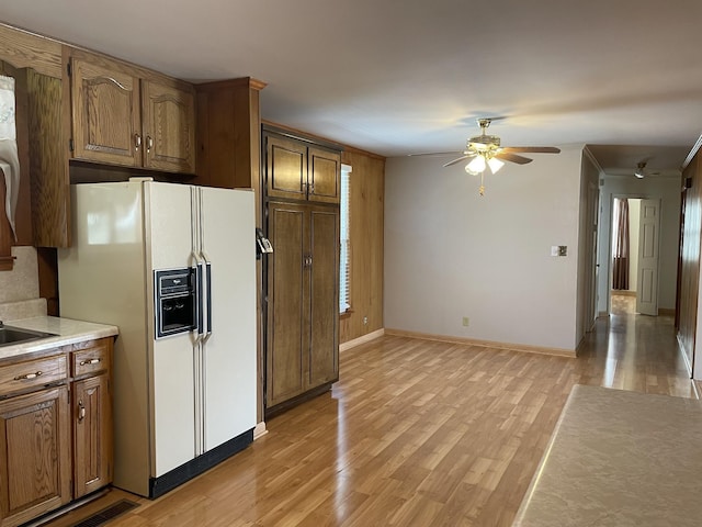 kitchen featuring ceiling fan, white fridge with ice dispenser, sink, and light hardwood / wood-style flooring