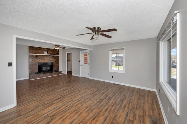 unfurnished living room featuring ceiling fan, dark hardwood / wood-style flooring, a wood stove, and a textured ceiling