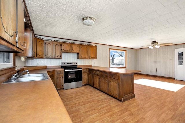 kitchen featuring stainless steel range with electric stovetop, sink, ceiling fan, light hardwood / wood-style floors, and kitchen peninsula