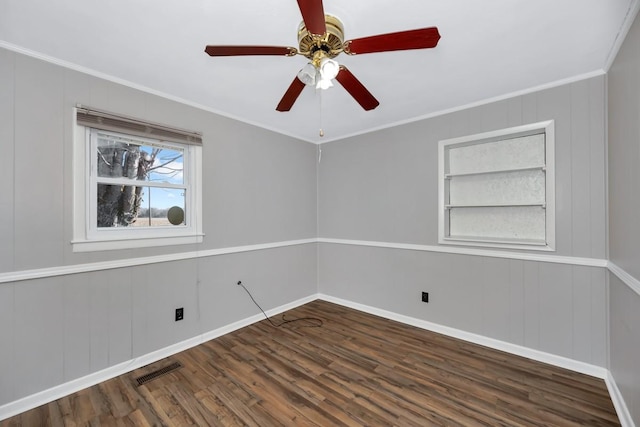 empty room with dark hardwood / wood-style flooring, built in features, and ornamental molding