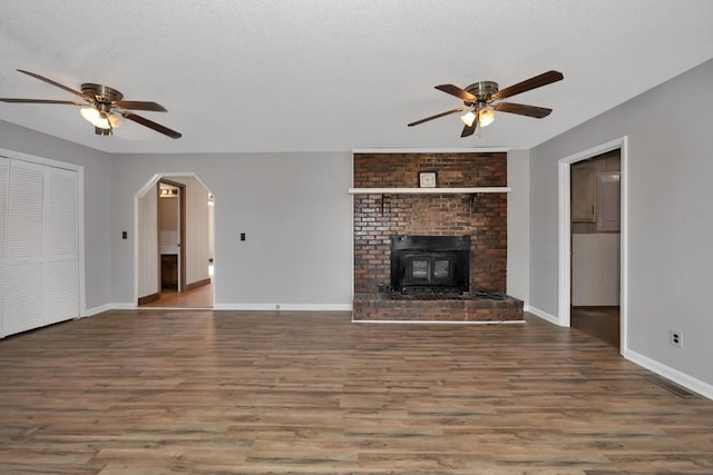 unfurnished living room featuring a wood stove, ceiling fan, and hardwood / wood-style floors