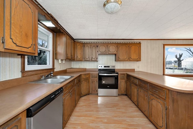 kitchen with crown molding, sink, light hardwood / wood-style flooring, appliances with stainless steel finishes, and kitchen peninsula