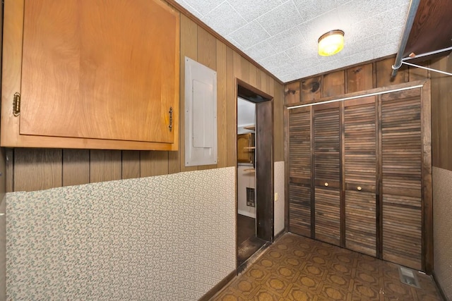 corridor featuring electric panel and wooden walls