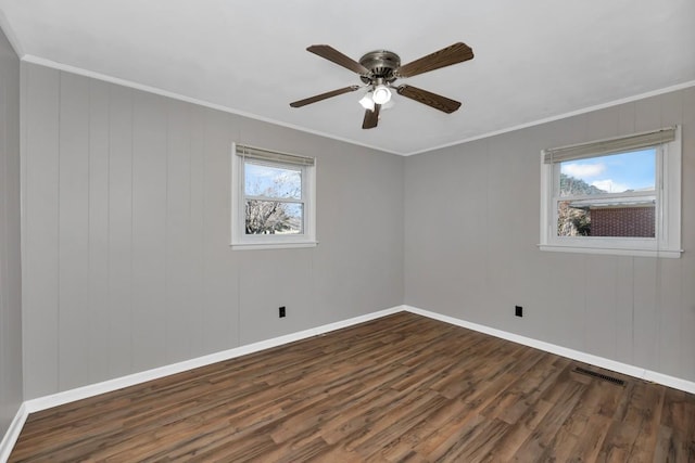 spare room featuring ornamental molding, dark wood-type flooring, and a wealth of natural light