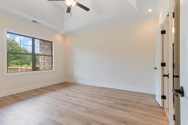 empty room with ceiling fan, light hardwood / wood-style floors, ornamental molding, and a tray ceiling