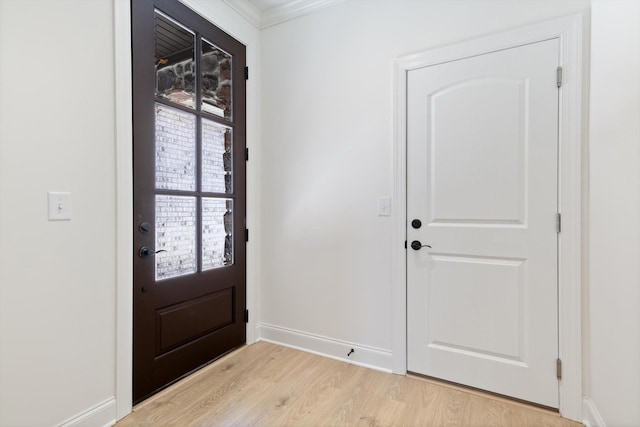 doorway featuring crown molding and light hardwood / wood-style floors