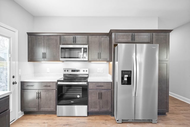 kitchen with appliances with stainless steel finishes, light wood-type flooring, and dark brown cabinets