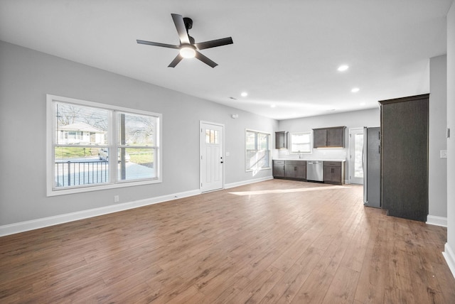 unfurnished living room with ceiling fan, light wood-type flooring, and sink