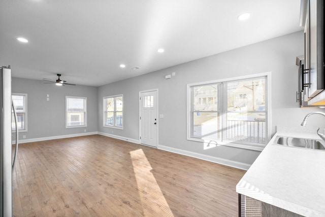 interior space with a wealth of natural light, sink, ceiling fan, and light hardwood / wood-style floors