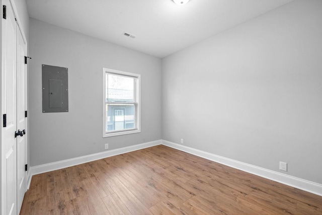 unfurnished room with electric panel and light hardwood / wood-style flooring