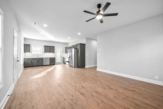 unfurnished living room featuring light hardwood / wood-style floors, ceiling fan, and sink