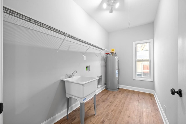 laundry room with light wood-type flooring, electric water heater, and hookup for a washing machine