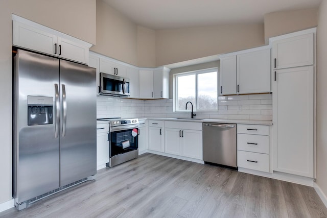 kitchen featuring high vaulted ceiling, white cabinets, sink, appliances with stainless steel finishes, and tasteful backsplash