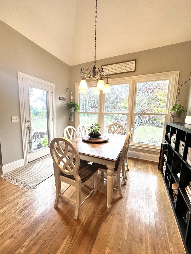 dining space with hardwood / wood-style flooring, lofted ceiling, and a notable chandelier