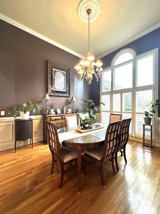 dining space with crown molding, light hardwood / wood-style flooring, and an inviting chandelier