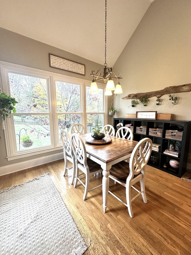 dining space featuring wood-type flooring, lofted ceiling, and a notable chandelier