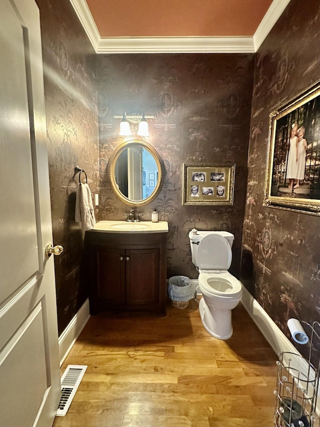 bathroom featuring hardwood / wood-style flooring, vanity, toilet, and ornamental molding