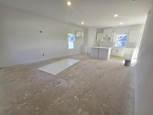 interior space featuring a center island, white cabinetry, and a wealth of natural light