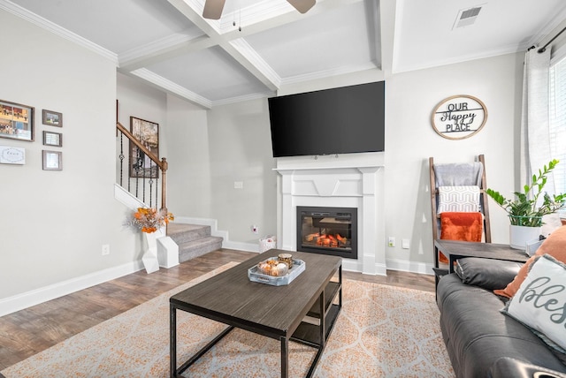 living room featuring beamed ceiling, light hardwood / wood-style flooring, ceiling fan, and ornamental molding