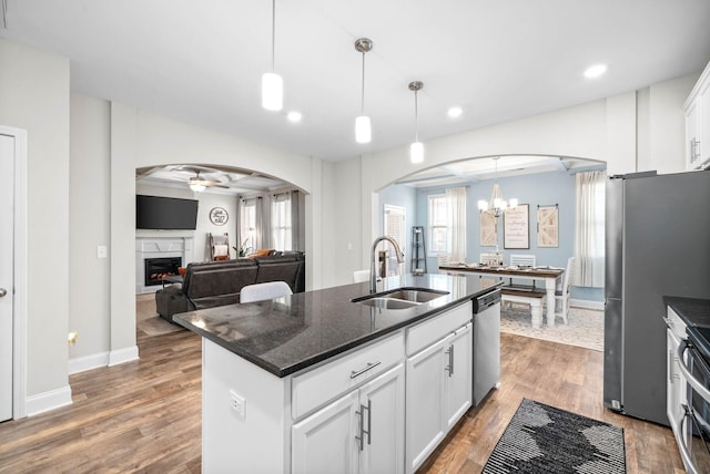 kitchen with white cabinetry, a center island with sink, decorative light fixtures, and sink