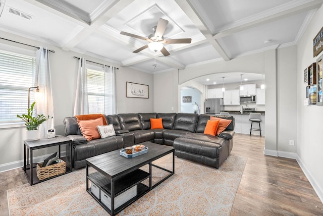 living room with ornamental molding, coffered ceiling, ceiling fan, beam ceiling, and light hardwood / wood-style floors