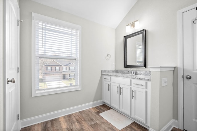 bathroom with hardwood / wood-style flooring, vanity, a healthy amount of sunlight, and lofted ceiling