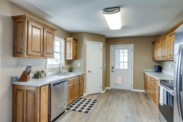 kitchen featuring sink, dishwasher, light hardwood / wood-style floors, and range