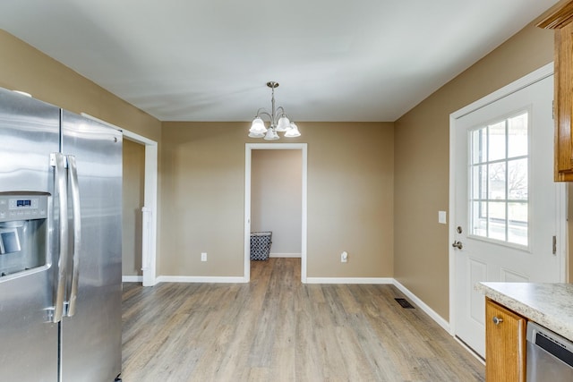 kitchen with hanging light fixtures, light hardwood / wood-style flooring, stainless steel appliances, and a notable chandelier