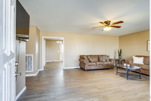 living room featuring ceiling fan with notable chandelier and hardwood / wood-style flooring