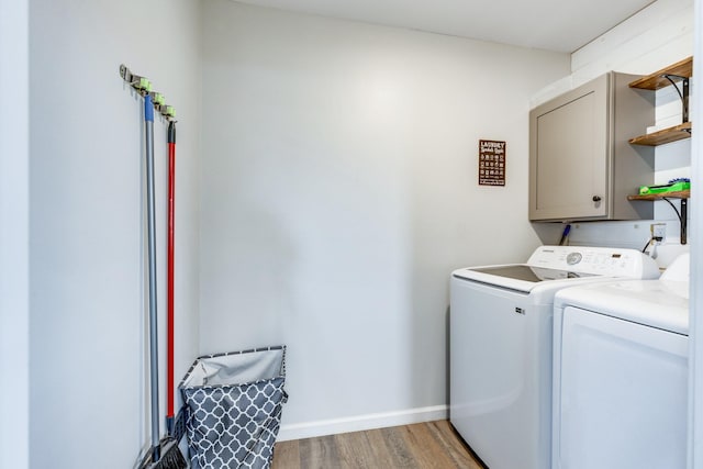 washroom with washing machine and dryer, cabinets, and light hardwood / wood-style floors