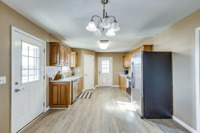 kitchen featuring pendant lighting, sink, light hardwood / wood-style floors, stainless steel appliances, and a chandelier