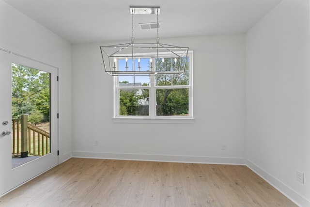 unfurnished dining area with light hardwood / wood-style flooring and a notable chandelier