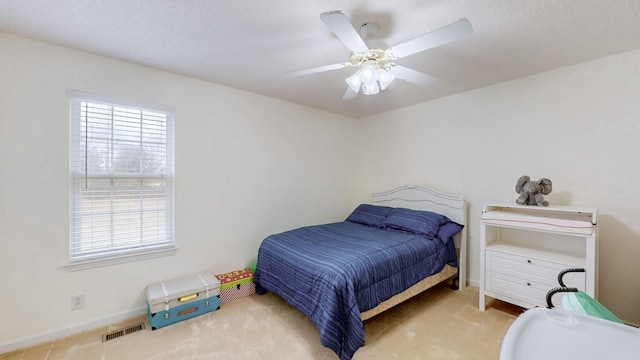 bedroom with a textured ceiling, light colored carpet, and ceiling fan