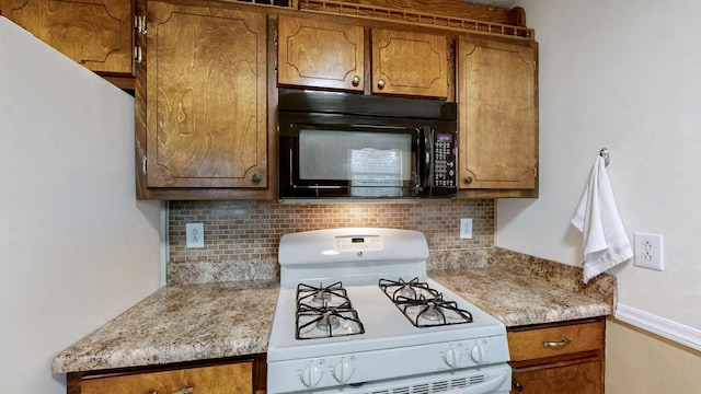 kitchen with tasteful backsplash, white gas range, and light stone counters