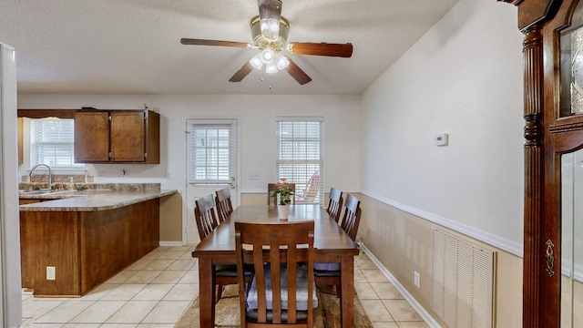 tiled dining space with a textured ceiling, ceiling fan, and sink