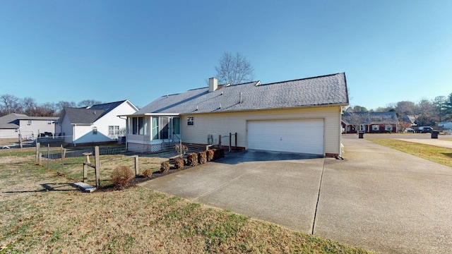 rear view of property featuring a garage, a lawn, and a sunroom