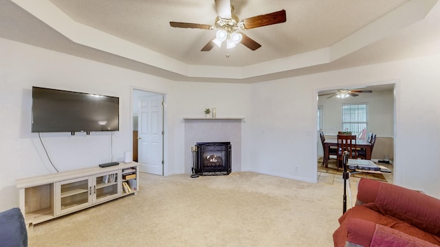 carpeted living room with a tray ceiling and ceiling fan